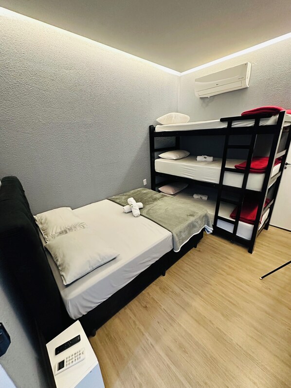 A bunk bed room with a control panel, a grey textured wall, and a wooden floor.
