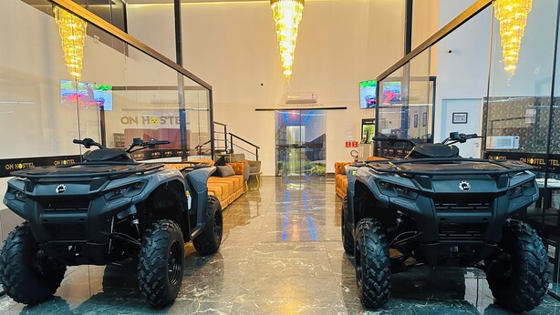 Un hall d’hôtel moderne avec deux quads garés au centre, un canapé et un lustre.