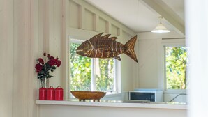 Eine Küche mit Fischdeko, einer Vase mit roten Rosen und einer Mikrowelle.