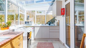 A modern kitchen with a glass roof, white cabinetry, and a wooden countertop. - 1 bedroom accommodation in Ventnor (Ventnor)