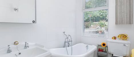 A bathroom with a white sink, a freestanding bathtub, and a toilet.