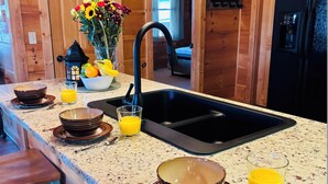 A kitchen with wooden cabinets, a granite countertop, a black sink, and a refrigerator.