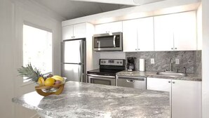 A modern kitchen with white cabinets, stainless steel appliances, and a granite countertop. - 2 BD/2BA VILLA WITH BOAT SLIP IN ISLAMORADA,FL (Islamorada)