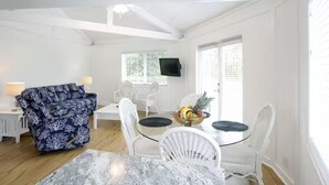 A spacious living area with a sofa, dining table, and chairs. There is a flat-screen TV mounted on the wall and a window with blinds. - 2 BD/2BA VILLA WITH BOAT SLIP IN ISLAMORADA,FL (Islamorada)