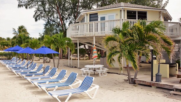 A beachside property with a pool, lounge chairs, and a dining area. - 2 BD/2BA VILLA WITH BOAT SLIP IN ISLAMORADA,FL (Islamorada)