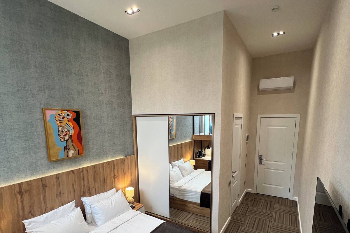 A hotel room with a large bed, a mirror, a painting on the wall, and a wooden headboard.