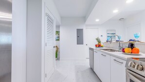A modern kitchen with white cabinetry, a stainless steel refrigerator, and a built-in oven. - Modern 1BR Apt in Hollywood, FL – 5 Mins to Beach, W/ Pool, Gym, & Free Parking (Hollywood)
