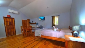 Ein Schlafzimmer mit Bett, Schreibtisch, Stuhl, Fernseher und einem Notausgang.