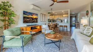 A modern living room with a sofa, coffee table, and chairs. There is a kitchen in the background with cabinets and a microwave. - Welcome to Mavi Bay, luxury ocean view condo,by Kamaole II beach newly renovated (Kihei)