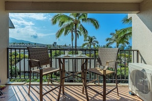 Relax on the balcony with a view of palm trees and distant mountains, enjoying the fresh air and dining space.