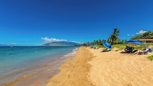 A beach with clear blue water, sandy shore, and umbrellas. - Welcome to Mavi Bay, luxury ocean view condo,by Kamaole II beach newly renovated (Kihei)