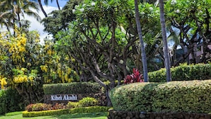 A well-maintained garden with a stone wall, lush greenery, and a sign reading "Kihei Akahi". - Welcome to Mavi Bay, luxury ocean view condo,by Kamaole II beach newly renovated (Kihei)