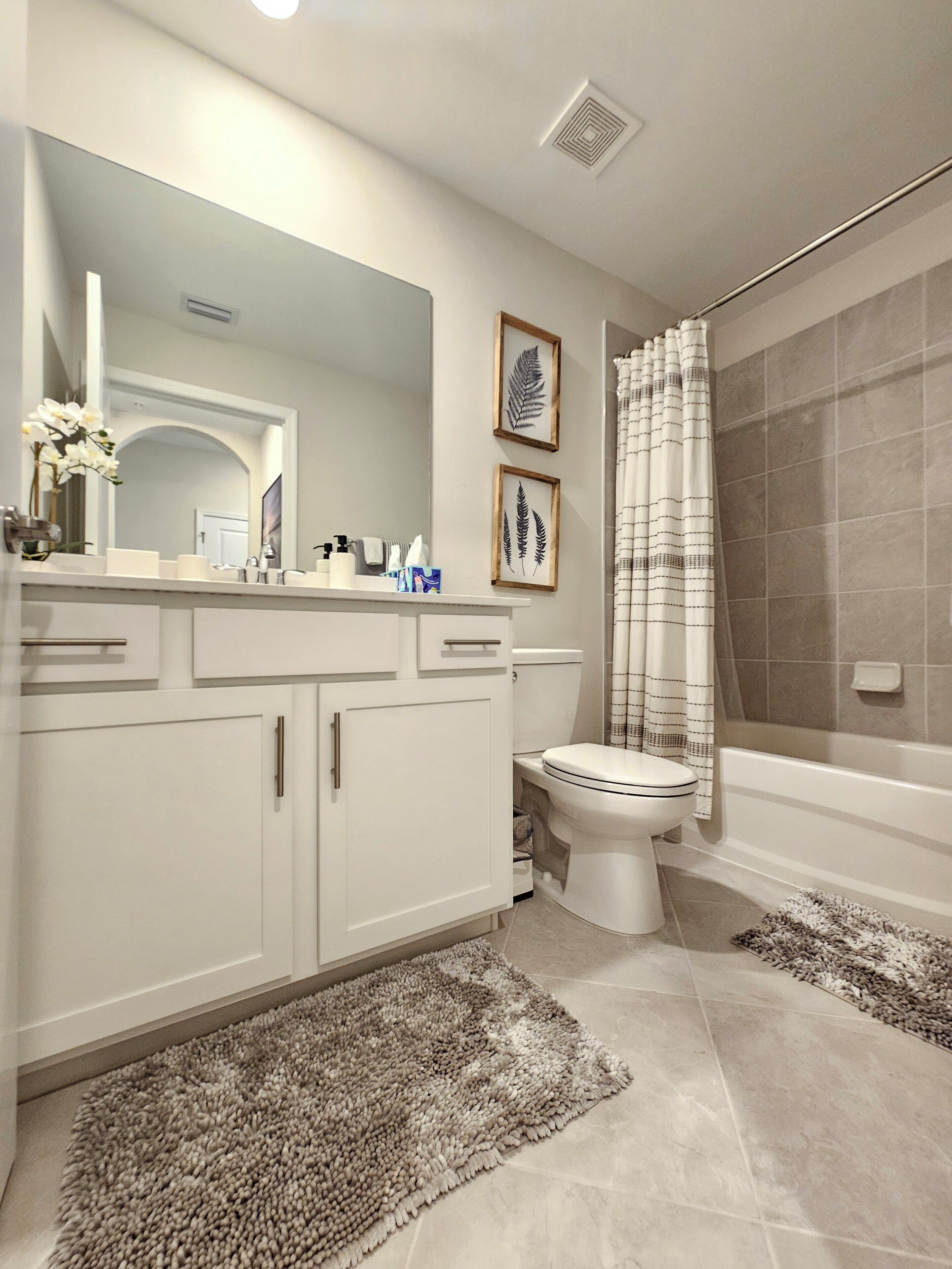 A modern bathroom with a white vanity, a toilet, and a shower area.