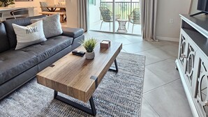 A modern living room with a grey sofa, a wooden coffee table, and a TV stand. -  18-hole Golf Course Condo. Two bedrooms-Two bath with amazing views  (Ave Maria)