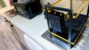 Une cuisine équipée d’un four à micro-ondes, d’un appareil noir doté d’un cadre jaune, et d’un lave-vaisselle.
