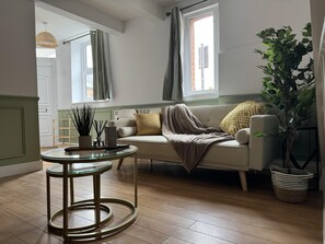 A living room with a sofa, a round glass table, a potted plant, and a window with curtains. - Grace House - Spacious 3 Bedroom Retreat (Reading)