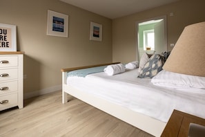 Ein Schlafzimmer mit einem Bett, einer Kommode und zwei gerahmten Bildern an der Wand.