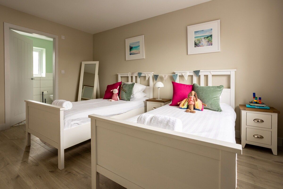 A bedroom with two beds, a bedside table, a nightstand, and a mirror.
