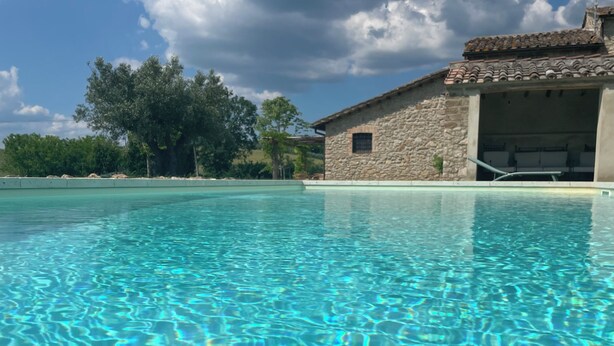 Une piscine aux eaux cristallines, avec un bâtiment en pierre en arrière-plan.