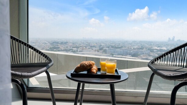 Ein Balkon mit Tisch, zwei Stühlen und einer Platte mit Croissants und Orangensaft.