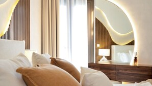 Ein Hotelzimmer mit Bett, Kissen, Nachttisch, Lampe und Spiegel.