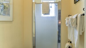Une salle de bain avec une porte de douche en verre, des toilettes et des serviettes suspendues sur un porte-serviettes.