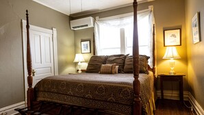 A four-poster bed with a wooden frame, a patterned bedspread, and a nightstand with a lamp.