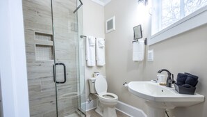 Ein modernes Badezimmer mit Duschkabine aus Glas, weißer Toilette und Standwaschbecken.