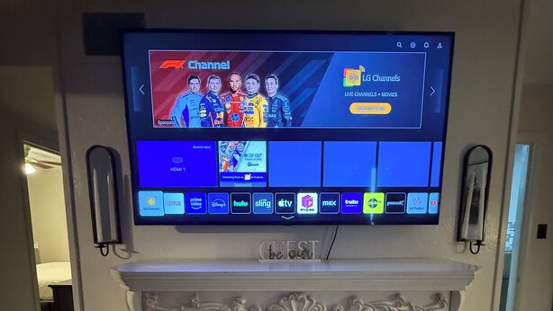 Een flatscreen-televisie bevestigd boven een witte schoorsteen met een brandend vuur.