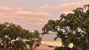 A coastal view with a flag, trees, and a road leading to the water. - Imagine Waking Up to This View! Relax at the 2 Bedroom Beach Condo in Biloxi, MS (Biloxi)