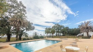 A swimming pool with lounge chairs and a palm tree. - Imagine Waking Up to This View! Relax at the 2 Bedroom Beach Condo in Biloxi, MS (Biloxi)