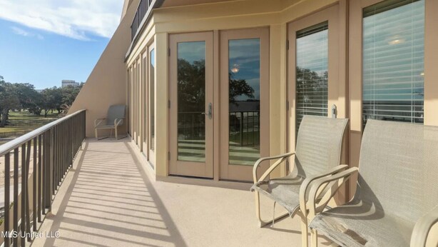 A balcony with a view of a park, a sliding glass door, and two chairs. - Imagine Waking Up to This View! Relax at the 2 Bedroom Beach Condo in Biloxi, MS (Biloxi)