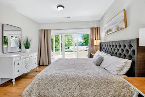 Un dormitorio con una cama grande, un aparador, un espejo y vistas al exterior.
