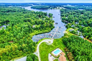 Vista aérea de una propiedad junto al lago con un puerto deportivo, piscina y amplias zonas boscosas.