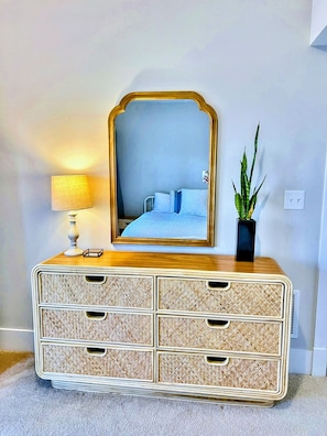 A dresser with a mirror, a lamp, and a potted plant.