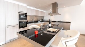 Une cuisine moderne dotée d’appareils électroménagers intégrés, d’un îlot central et d’un coin repas avec une chaise blanche.