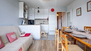 Un espacio habitable compacto con kitchenette, comedor y sofá con cojines estampados de corazones.