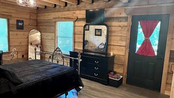 Een slaapkamer in een blokhut met een bed, een kaptafel, een dressoir en een spiegel.