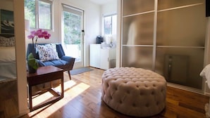 En moderne stue med sofa, skammel og et lille bord med en plante.