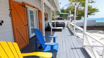 A wooden deck with outdoor seating and a view of the sea.