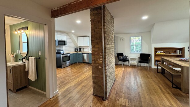A spacious kitchen with modern appliances, a dining area with a wooden table, and a brick column in the center. - Lovely house off Main Street (Hamilton)