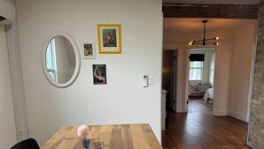 A dining area with a wooden table, a mirror, framed pictures, and a view into another room. - Lovely house off Main Street (Hamilton)