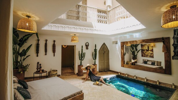Ein geräumiges Zimmer mit einem großen Bett, einem kleinen Pool und einer hohen Decke mit einem Oberlicht.