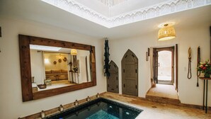 Ein Zimmer mit einem großen Spiegel, einem Pool und einer traditionellen Tür.