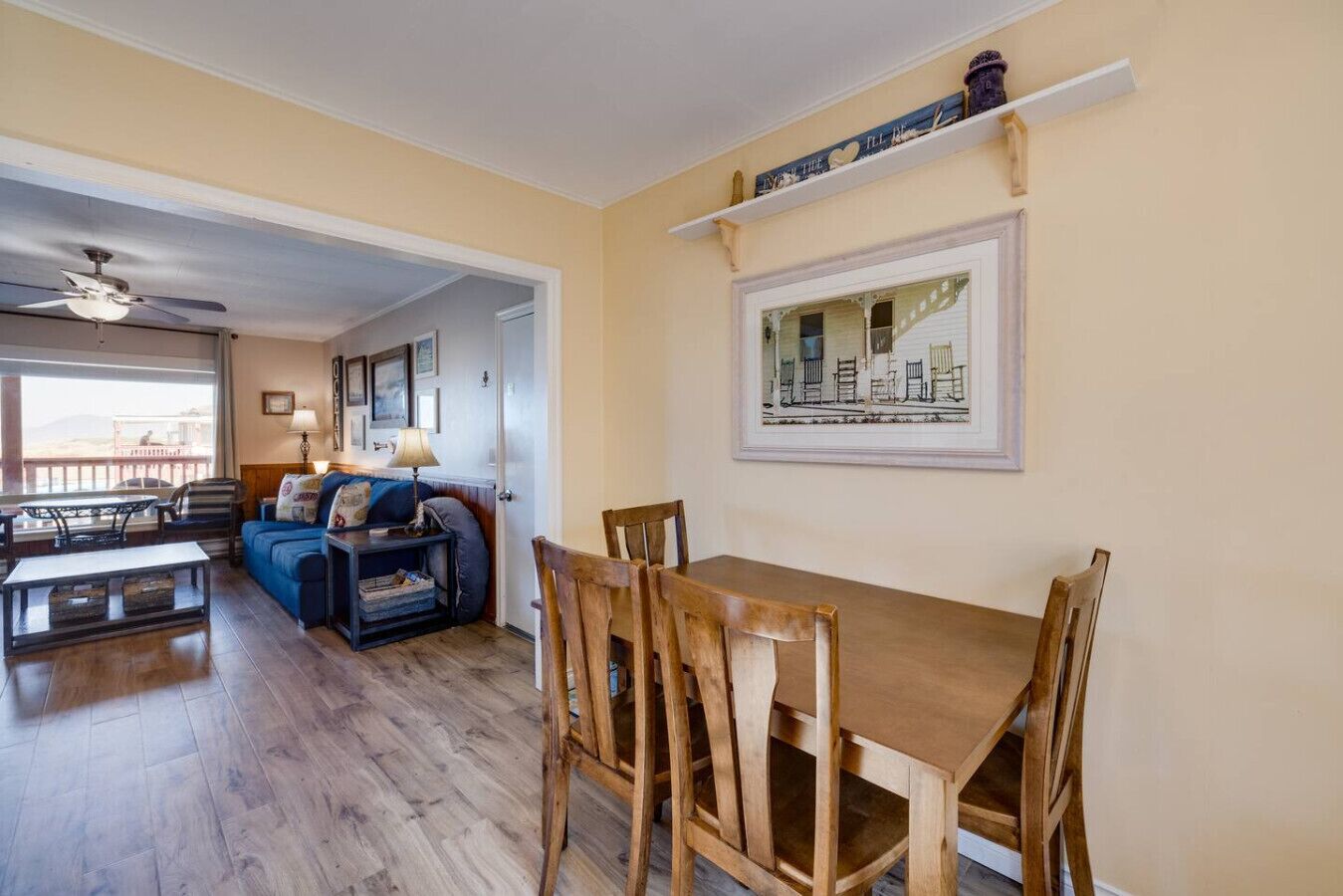 A dining area with a wooden table and chairs, a sofa, and a ceiling fan.