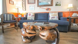 A cozy living room with a blue sofa, striped armchair, and a unique wooden coffee table. - Dog-Friendly Oceanview Getaway Condo #9 (Rockaway Beach)