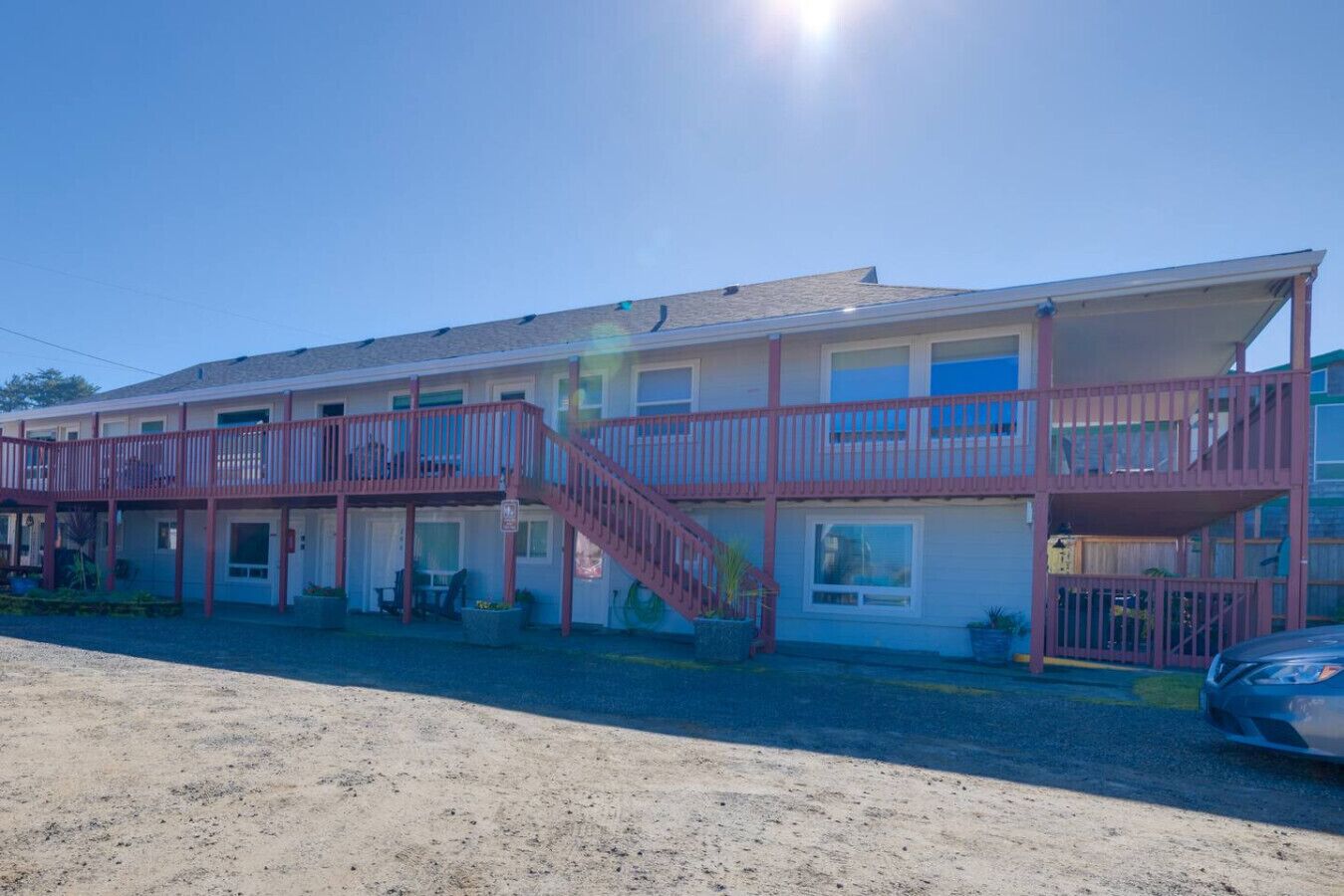 A motel with a two-story structure, a central staircase, and a covered outdoor area.