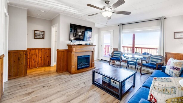 A living room with a fireplace, a television, a ceiling fan, and a view of the outdoors. - Dog-Friendly Oceanview Getaway Condo #9 (Rockaway Beach)