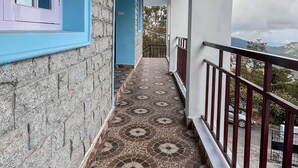 Een overdekt balkon met een vloer met patroon, een stenen muur en uitzicht op het landschap.