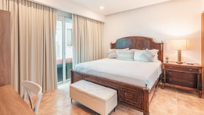 A bedroom with a wooden bed, a bedside table with a lamp, a bench, and a chair.